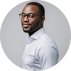 Portrait of a smiling Black man wearing glasses and a white shirt against a gray background.